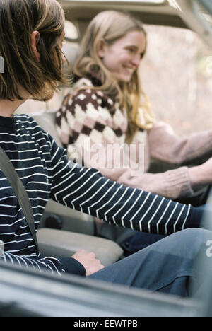 Sorridente coppia giovane guida nella loro auto. Foto Stock