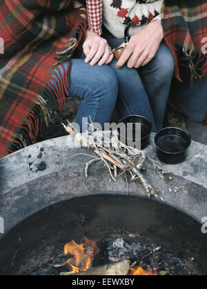 Dettaglio del giovane seduto da un una buca per il fuoco. Foto Stock