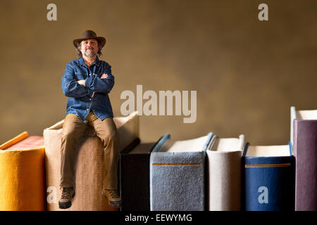 L'uomo con il cappello di seduta sul libro Foto Stock