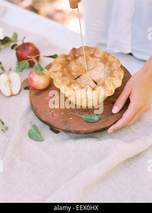 Donna in piedi a una tabella con gli alimenti, una fetta di torta di mele. Foto Stock