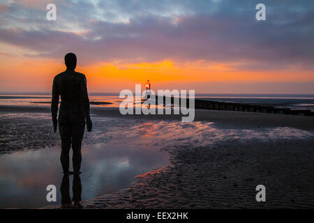 Formby - scialuppa di salvataggio Road Beach, Liverpool, Merseyside Regno Unito 22 Gennaio, 2015. Regno Unito Meteo. Ghisa uomini in piedi in una pozzanghera sulla spiaggia guardare il mare e il sole di setting. La calma della sera dopo una marea alta su Crosby Beach. Un altro luogo figure - ciascuno del peso di 650 chili - sono realizzati da calchi dell'artista, ( Anthony Gormley), proprio corpo permanente sulla spiaggia, tutti di loro che guarda al mare. Avendo già visto in Cuxhaven in Germania, Stavanger in Norvegia e De Panne in Belgio, 'un altro posto' è ora una caratteristica permanente nel Regno Unito. Foto Stock