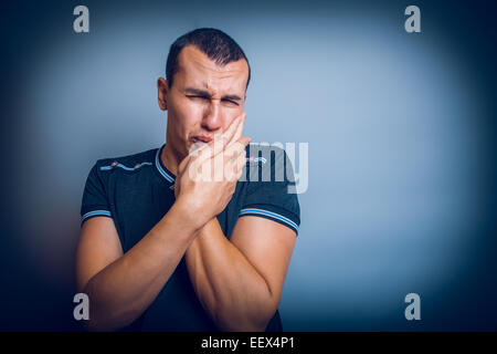 L'uomo di aspetto europeo brunet premuta una mano al suo chee Foto Stock