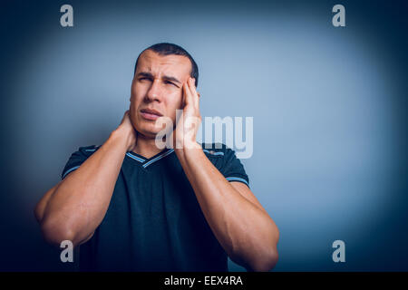 Brunet l uomo di aspetto europeo tiene le mani dietro la sua hea Foto Stock