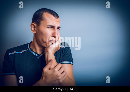 Brunet l uomo di aspetto europeo con la sua mano sulla guancia Foto Stock