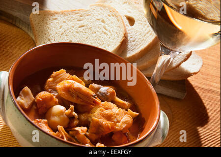 Ciotola di zuppa di pesce fresco, pane e vino bianco Foto Stock