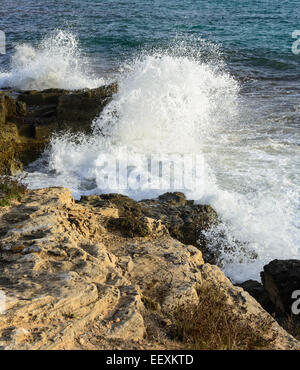 Come onde selvagge con seaspray schiantarsi su rocce calcaree su un bel pomeriggio di sole di Maiorca. Foto Stock