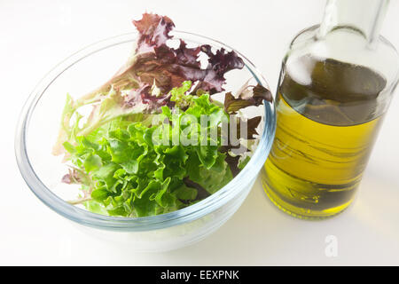 Miscelati rosso e verde lattuga multilamina foglie in una ciotola di vetro con olio extra vergine di oliva Foto Stock