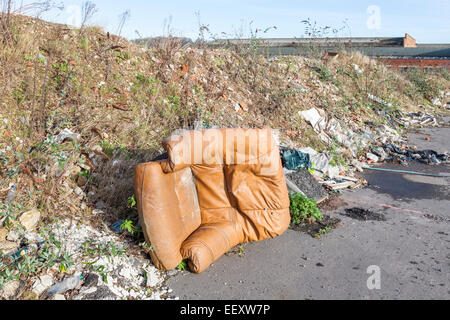 Volare il ribaltamento. Scarico illegale di una poltrona in pelle, rifiuti e altri rifiuti su un marciapiede sulla periferia di una città. Nottingham, Inghilterra, Regno Unito Foto Stock