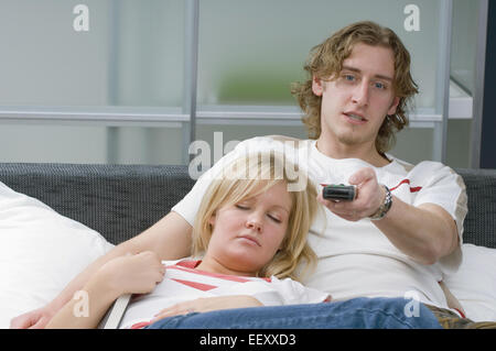 Giovane rilassante e disteso su un letto mentre guardi la televisione Foto Stock