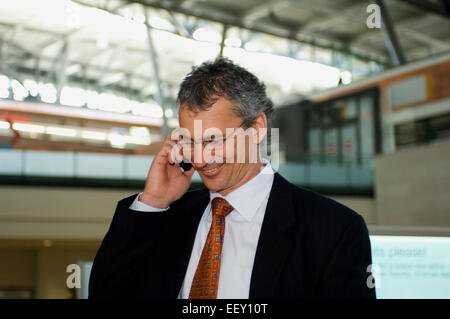 Imprenditore in aeroporto utilizzando assistente digitale personale Foto Stock