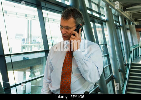 Imprenditore in aeroporto utilizzando assistente digitale personale Foto Stock