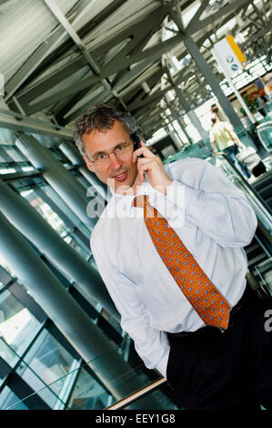 Imprenditore in aeroporto utilizzando assistente digitale personale Foto Stock