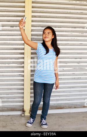 Giovani asiatici adolescente tenendo selfie in strada Foto Stock