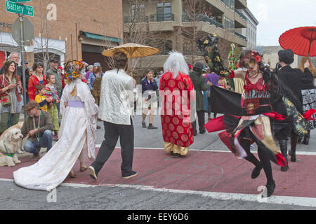 Persone indossano coloratissimi costumi e maschere e spontaneamente la danza come si cammina nella primavera Asheville, NC Mardi Gras Parade Foto Stock