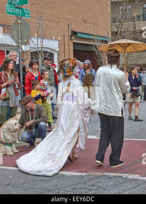 Persone che indossano costumi colorati, un ombrellone, maschere e le espressioni a piedi nella primavera del Mardi Gras Parade Foto Stock