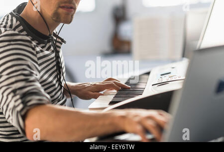 Uomo con notebook e synth per rendere la musica Foto Stock