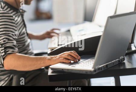 Uomo con notebook e synth per rendere la musica Foto Stock