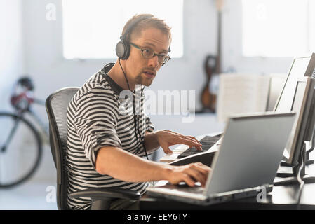 Uomo con notebook e synth per rendere la musica Foto Stock