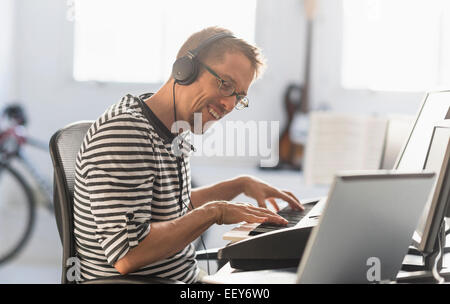 Uomo con notebook e synth per rendere la musica Foto Stock