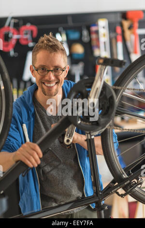 Uomo che ripara bici nel negozio Foto Stock