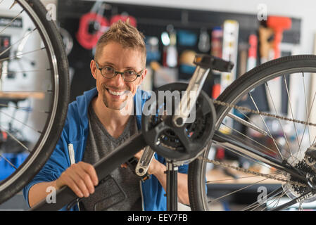 Uomo che ripara bici nel negozio Foto Stock