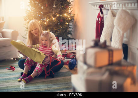 Madre e figlia (4-5) apertura regali di natale Foto Stock