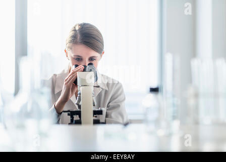 Femmina tecnico di laboratorio analisi il campione attraverso il microscopio Foto Stock
