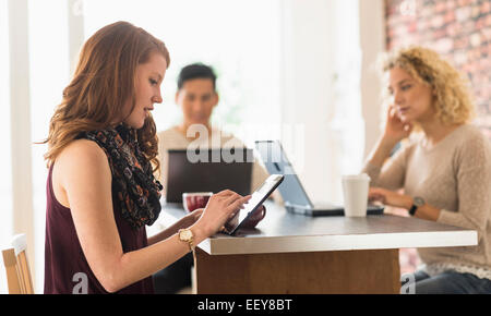 Giovane donna seduta al cafe e con tavoletta digitale Foto Stock