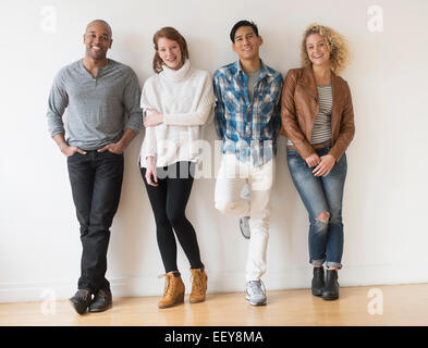 Gruppo di amici in piedi di fronte a muro bianco Foto Stock