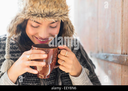 Ritratto di sorridente giovane donna di bere dalla tazza Foto Stock