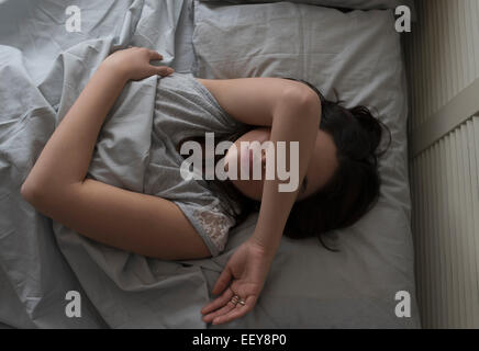 Vista in elevazione della giovane donna che dorme nel letto Foto Stock