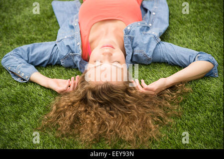 Giovane donna sdraiata su un prato Foto Stock