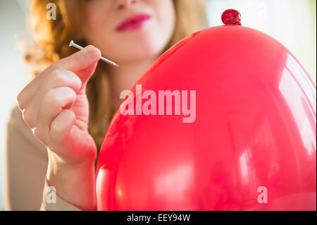 Giovane donna palloncino popping Foto Stock