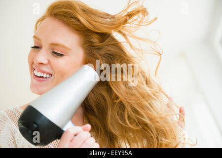 Donna soffiare i capelli di essiccazione Foto Stock