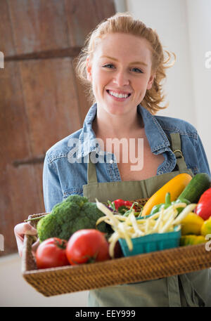 Ritratto di giovane donna tenendo il vassoio con le verdure Foto Stock