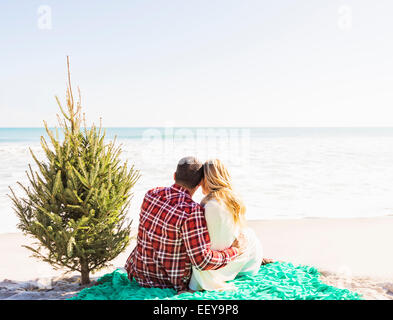 Stati Uniti d'America, Florida, Giove, amare giovane seduto sulla spiaggia con struttura ad albero Foto Stock