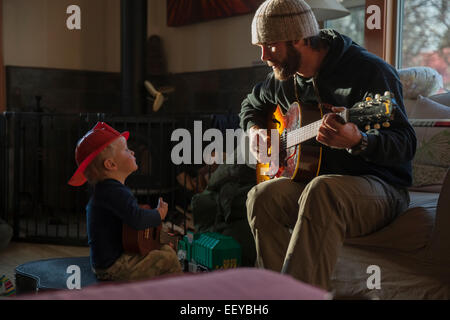 Ragazzo (4-5) Ascoltando il suo papà a suonare la chitarra Foto Stock