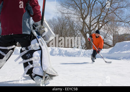 Ragazzi giocare hockey su ghiaccio su una pista di pattinaggio all'aperto Foto Stock