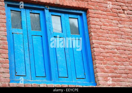 Il blu di legno verniciato doble finestra sul rosso mattone a parete di facciata tradizionale stile newar casa in Godawari-Lalitpur distr.-Bagmati Foto Stock