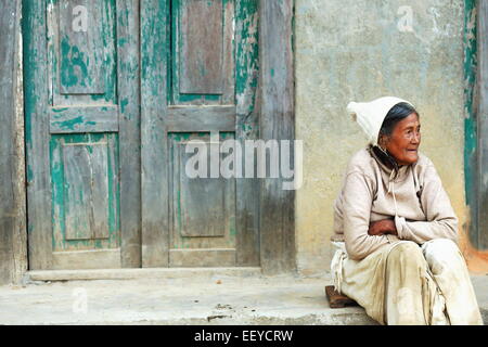 GODAWARI, Nepal - 15 ottobre: vecchia donna nepalese si siede sul pavimento prima che la vernice verde sfumato porta della sua casa in Godawari Foto Stock