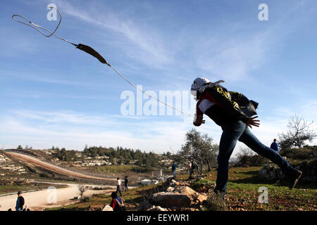 Ramallah, West Bank. 24 gen 2015. Un manifestante palestinese utilizza un slingshot a lanciare pietre alle forze di sicurezza israeliane durante scontri nei pressi di Israele Ofer prigione. © Shadi Hatem APA/images/ZUMA filo/Alamy Live News Foto Stock