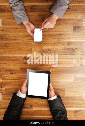 Uomo e donna che lavorano su dispositivi mobili. Scattato dalla vista di cui sopra Foto Stock