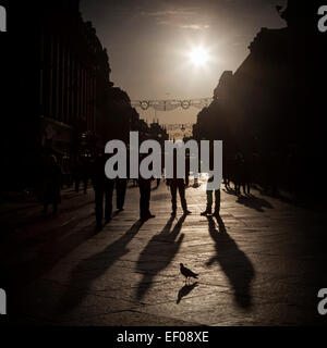 Persone che camminano giù il high street nel tardo pomeriggio Foto Stock