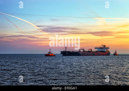 Nave cisterna con la scorta rimorchiatori sul mare a sunrise. Foto Stock