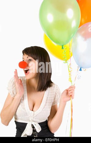 Donna che indossa un clown naso e palloncini di contenimento Foto Stock