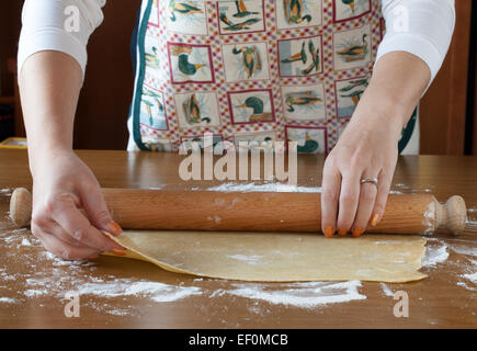 Stendere il foglio di pasta sulla tavola di legno Foto Stock