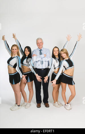 Cheerleader in piedi con docente Foto Stock