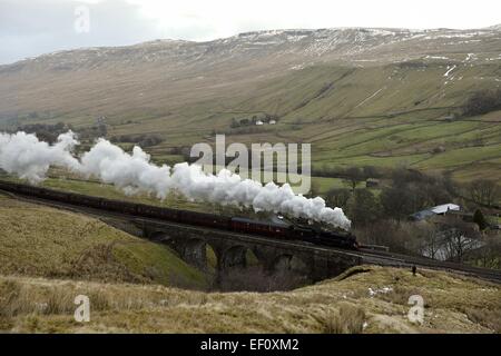 Pennines, Cumbria, Regno Unito. Il 24 gennaio, 2015. Regno Unito più blande condizioni atmosferiche. La Cumbria montagna invernale Express vapori attraverso la neve di fusione dei Pennines della Cumbria come ottenere temperature più miti. La prima speciale di vapore treno di bolina del 2015 sulla storica Carlisle per estinguere la linea ferroviaria. Locomotiva n. 45407 "Lancashire Fusilier' si arrampica su Ais Gill viadotto facendo una buona testa di vapore sulla lunga salita al vertice di Ais Gill che a 847 metri è il più alto vertice ferroviaria in Inghilterra. Credito: STUART WALKER/Alamy Live News Foto Stock