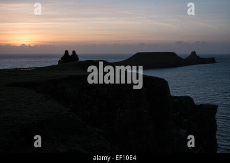 Walkers silhouette al tramonto su un terribilmente freddo,soleggiato e ventoso giorno al worm di testa,Rhossili Beach Bay,Gower Peninsula, Wales, Regno Unito, Foto Stock