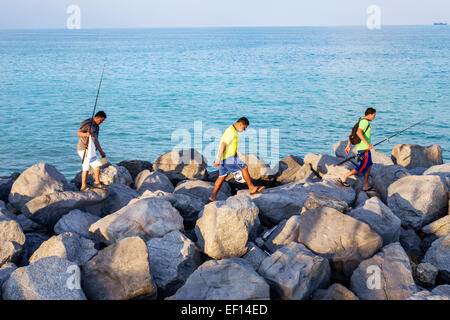 Miami Beach Florida,Oceano Atlantico,molo di roccia,frangiflutti,latini ispanici asiatici,uomo maschio,amici,arrampicata su,pesca in corso,canne,pali,FL14110701 Foto Stock